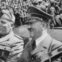 Adolf Hitler und Benito Mussolini sitzen am Rücksitz eines Autos. Im Hintergrund ist eine große Menschenmenge zu sehen. | Adolf Hitler (hier mit Italiens Diktator Benito Mussolini) hatte bekanntlich starken Mundgeruch - ein Symptom des Kallmann-Syndroms