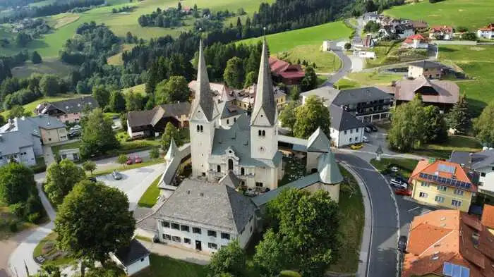 Zu sehen ist eine Luftaufnahme einer Kirche, die in einem Ortskern steht