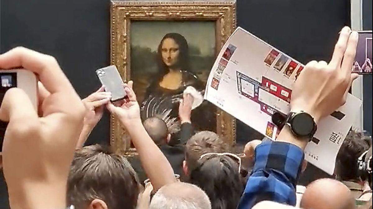 Ein Mitarbeiter des Louvre reinigt die Mona Lisa nach der Attacke mit einer Torte 