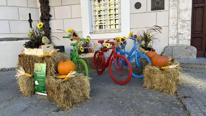Bunt angemalte Fahrräder stehen zwischen Heuballen und Kürbissen vor der Liebburg in Lienz