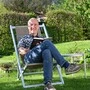 Dieter Mayr-Hassler sitzt in einem Stuhl vor seinem Hotel und liest ein Buch