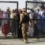 CORRECTION / A Pakistani soldier holds a gate as Afghan and Pakistani people wait to enter Afghanistan through the Pakistan-Afghanistan border crossing point in Chaman on August 27, 2021 following the Taliban's stunning military takeover of Afghanistan. (Photo by - / AFP) / ìThe erroneous mention[s] appearing in the metadata of this photo by - has been modified in AFP systems in the following manner: [to enter Afghanistan] instead of [to enter Pakistan]. Please immediately remove the erroneous mention[s] from all your online services and delete it (them) from your servers. If you have been authorized by AFP to distribute it (them) to third parties, please ensure that the same actions are carried out by them. Failure to promptly comply with these instructions will entail liability on your part for any continued or post notification usage. Therefore we thank you very much for all your attention and prompt action. We are sorry for the inconvenience this notification may cause and remain at your disposal for any further information you may require.î
