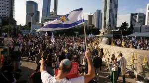 People gather to watch a live broadcast of Israeli hostages released from Gaza at a plaza known as hostages square in Tel Aviv, Israel, Monday, Oct. 13, 2025. The release took place as part of a cease-fire agreement between Israel and Hamas. (AP Photo/Oded Balilty)