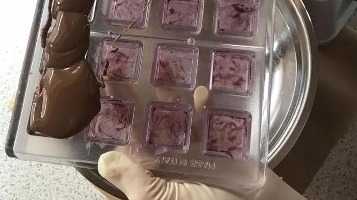 Nachdem die Formen mit Watte auspoliert wurden, werden sie mit eingefärbter Kakaobutter ausgemalt. Um einen besseren Effekt zu erzeugen, nimmt Gruber meist zwei Farben hintereinander. Danach wird die Kuvertüre eingegossen.