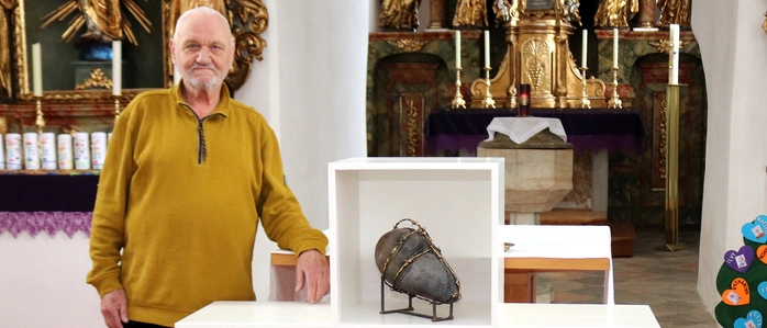 Älterer Herr mit Kunstinstallation in Kreuzform in einer Kirche