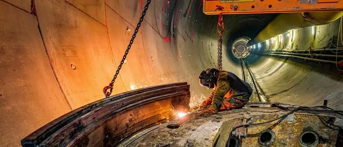Blick in die Tunnelröhre des Semmering-Basistunnels, im Vordergrund ein Arbeiter bei Schweißarbeiten