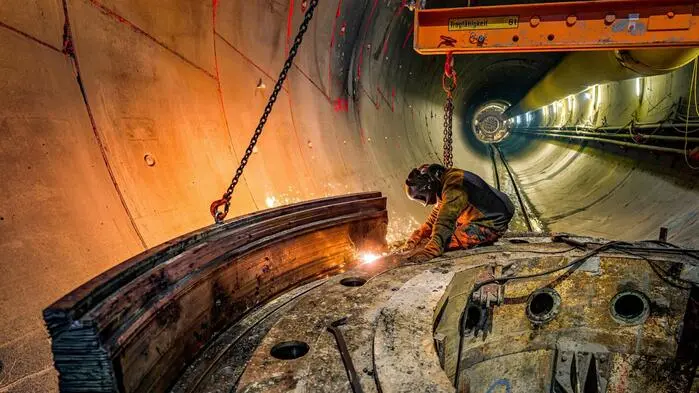 Blick in die Tunnelröhre des Semmering-Basistunnels, im Vordergrund ein Arbeiter bei Schweißarbeiten