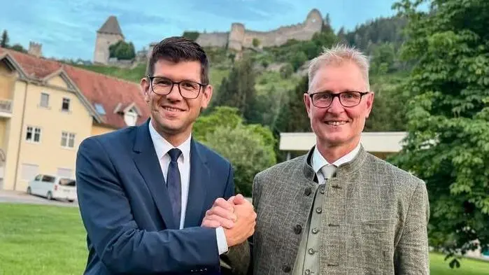 Zwei Männer klatschen ab und lächeln in die Kamera.