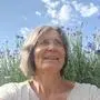 Eine Frau sitzt vor blauen Kräuterblüten
