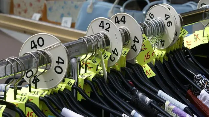 Auf einem Kleiderständer hängt Kleidung unterschiedlicher Größen