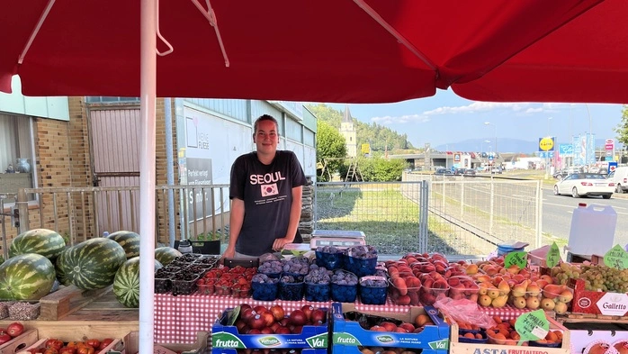 Die Verkäuferin steht an ihrem Obst- und Gemüsestand