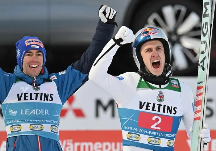 Austria's Daniel Tschofenig (R) stands next to his compatriot Austria's Stefan Kraft as he reacts after his second jump during the competition at the second leg of the Four Hills Ski Jumping tournament (Vierschanzentournee), in Garmisch-Partenkirchen, southern Germany, on January 1, 2025. (Photo by KERSTIN JOENSSON / AFP)