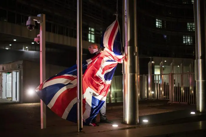 FILE - In this Wednesday, Dec. 9, 2020 file photo, a worker raises the Union Flag prior a meeting between European Commission President Ursula von der Leyen and British Prime Minister Boris Johnson at EU headquarters in Brussels. Relations between the European Union and recently departed Britain took another diplomatic dip on Wednesday, March 10, 2021 when the EU envoy in London was summoned to explain comments that Britain had issued a vaccine export ban. (AP Photo/Francisco Seco, File)