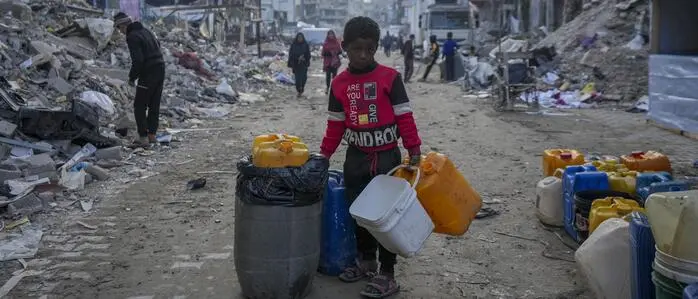 A young Palestinian kid carries jerricans along the destruction caused by the Israeli air and ground offensive in Jabaliya, Gaza Strip, Wednesday, Feb. 5, 2025. (AP Photo/Abdel Kareem Hana)