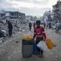 A young Palestinian kid carries jerricans along the destruction caused by the Israeli air and ground offensive in Jabaliya, Gaza Strip, Wednesday, Feb. 5, 2025. (AP Photo/Abdel Kareem Hana)