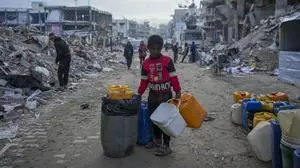 A young Palestinian kid carries jerricans along the destruction caused by the Israeli air and ground offensive in Jabaliya, Gaza Strip, Wednesday, Feb. 5, 2025. (AP Photo/Abdel Kareem Hana)