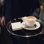 Ein Kellner serviert einen Cappuccino 