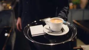Ein Kellner serviert einen Cappuccino 