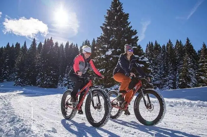 Fat E-Biking in Ponte di Legno. Für die Wintersaison 2018/19 hat sich die Skischule Pontedilegno in der Lombardei etwas ganz besonderes einfallen lassen: Mit den elektrisch betriebenen Fatbikes kann die atemberaubende Winterlandschaft rund um den Skiort Ponte di Legno nun bequem auf zwei Rädern erkundet werden. Ortskundige Guides führen Gäste jeden Mittwochabend auf Fatbikes durch die idyllischen Wälder der Umgebung, um den Sonnenuntergang an einem Aussichtspunkt mit Blick auf die umliegende Berglandschaft zu genießen. Nach einer kurzen Einführung können bereits Anfänger an den rund 1-stündigen Touren teilnehmen. Der Vorteil zu handelsüblichen Mountainbikes sind die extra breiten Reifen (bis zu 4,8 Zoll) der Fatbikes, die das Vorankommen im Schnee besonders einfach machen. Durch ihren festen Untergrund eignen sich im speziellen Winterwanderwege dazu, mit Fatbikes befahren zu werden. Wer sich auf den Bikes bereits sicher fühlt und die Gegend rund um Ponte di Legno gerne auf eigene Faust entdecken möchte, kann die Fatbikes bei der Pontedilegno Ski School auch stunden- oder tageweise ausleihen.