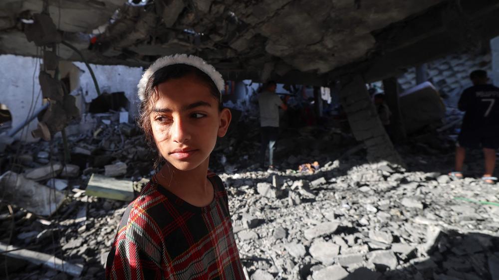 Kinder sehen sich ein in der vergangenen Nacht durch israelischen Beschuss zerstörtes Gebäude in Rafah im südlichen Gazastreifen an. (Symbolfoto)