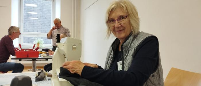 Frau Elisabeth nimmt beim Repair-Café in Voitsberg kleine Ausbesserungen an Kleidungsstücken vor