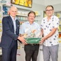 Drei Männer stehen in einer neu eröffneten Postfiliale 