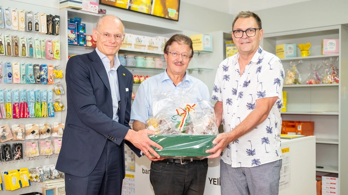 Drei Männer stehen in einer neu eröffneten Postfiliale