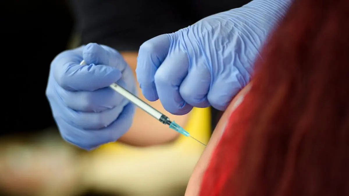 ABD0047_20210814 - KIEL - DEUTSCHLAND: dpatopbilder - 14.08.2021, Schleswig-Holstein, Kiel: Eine Mitarbeiterin des Deutschen Roten Kreuzes impft KielerInnen in einer mobilen Impfstation in einem Bus der Kieler Verkehrsbetriebe auf einem Parkplatz neben dem Stadion des Fußball-Zweitligisten KSV Holstein vor Beginn eines Fußballspieles des Vereins. Foto: Gregor Fischer/dpa +++ dpa-Bildfunk +++. - FOTO: APA/dpa/Gregor Fischer