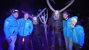 Zwei Krampusse in der Mitte, rundherum sind drei Männer und eine Frau in blauen Jacken | Krampusse und Perchten waren in Lendorf los