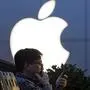 FILE - In this Friday, May 13, 2016, file photo, a man uses his mobile phone near an Apple store in Beijing. Apple reports financial results Tuesday, July 26, 2016. (AP Photo/Ng Han Guan, File)