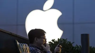 FILE - In this Friday, May 13, 2016, file photo, a man uses his mobile phone near an Apple store in Beijing. Apple reports financial results Tuesday, July 26, 2016. (AP Photo/Ng Han Guan, File)