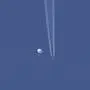 In this photo provided by Brian Branch, a large balloon drifts above the Kingston, N.C. area, with an airplane and its contrail seen below it. The United States says it is a Chinese spy balloon moving east over America at an altitude of about 60,000 feet (18,600 meters), but China insists the balloon is just an errant civilian airship used mainly for meteorological research that went off course due to winds and has only limited “self-steering” capabilities. (Brian Branch via AP)