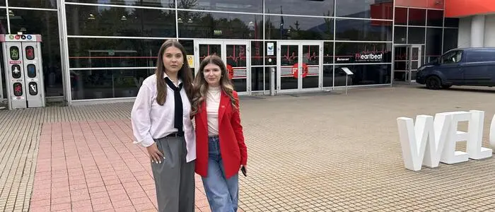 Zwei junge Frauen stehen vor einem Fachhochschulgebäude