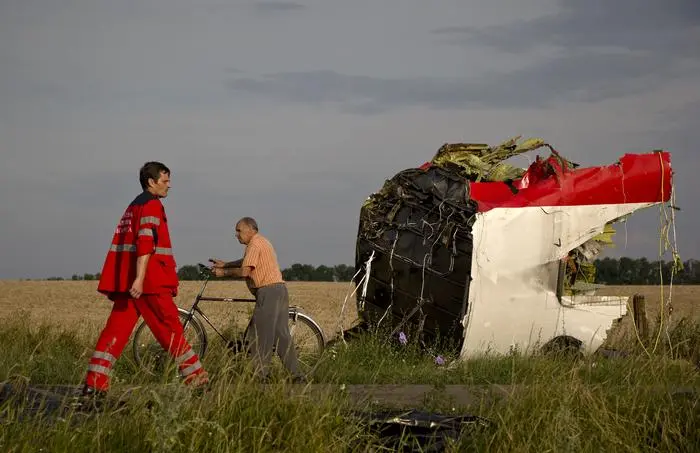 FILE - A paramedic walks by a part of fuselage at the crash site of Malaysia Airlines Flight 17 near the village of Hrabove, eastern Ukraine, on July 19, 2014. A Dutch court on Thursday is set to deliver verdicts in the long-running trial of three Russians and a Ukrainian rebel for their alleged roles in the shooting down of Malaysia Airlines flight MH17 over conflict-torn eastern Ukraine. (AP Photo/Vadim Ghirda, File)