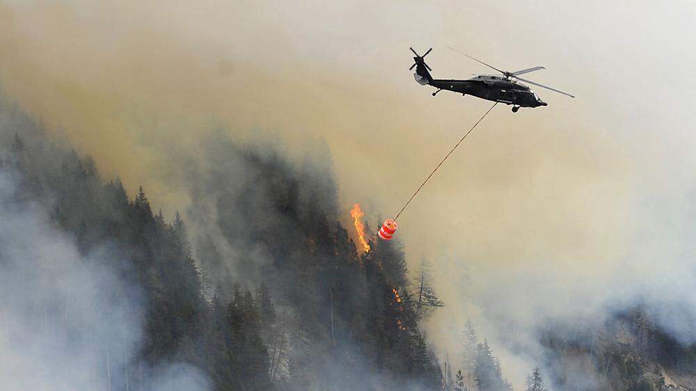 Hubschrauber fliegen Wasser auf den brennenden Berg