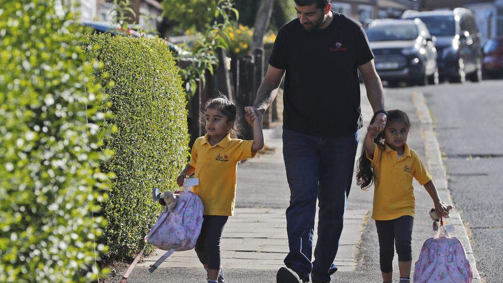 Ein Vater in London bringt seine zwei Kinder in die Vorschule.