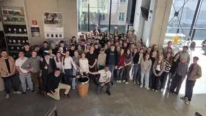 Blick von oben auf eine Gruppe von Schülerinnen und Schülern und Lehrern in einer Aula