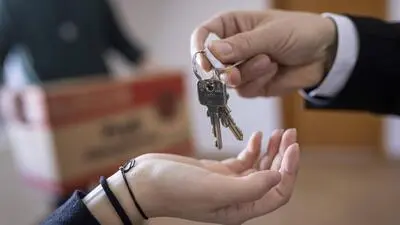 Hand reicht einer zweiten Hand einen Haustürschlüssel