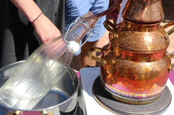 Anschließend wird die Destille mit Wasser befüllt und auf eine Herdplatte gestellt. Wenn dass destillierte Wasser durch den Lavendel nach oben wandert und die Öle und Duftstoffe löst, kondensiert es oben, weil hier mit kaltem Wasser gekühlt wird. Dadurch tröpfelt das Hydrolat dann durch ein Abflussrohr in die vorbereitete Flasche.