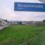 Man sieht eine große Wiesenfläche und ein Straßenschild mit der Aufschrift Mozartstraße – Gries 