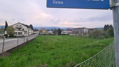 Man sieht eine große Wiesenfläche und ein Straßenschild mit der Aufschrift Mozartstraße – Gries 