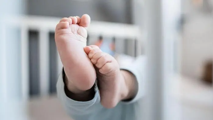 Füße eines Babys, das in einem Gitterbett liegt.
