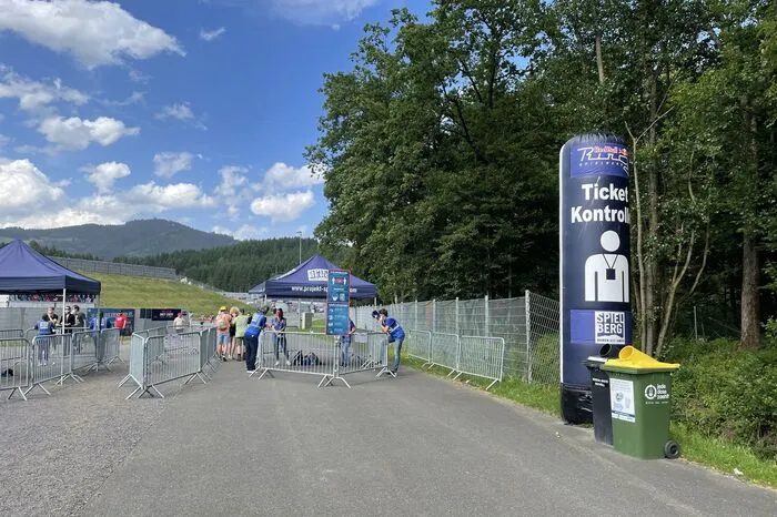 Weiter geht's am Ring-Gelände entlang zum nächsten Checkpoint. Hier wird erst Fieber gemessen, dann muss man sein Ticket zeigen. Masken sind hier Pflicht, auch wenn einige Besucher sie im Freien aufgrund der Hitze immer wieder abnehmen.