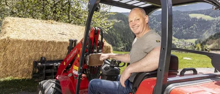 Ein Mann sitzt auf einem Gabelstapler und lächelt zufrieden.