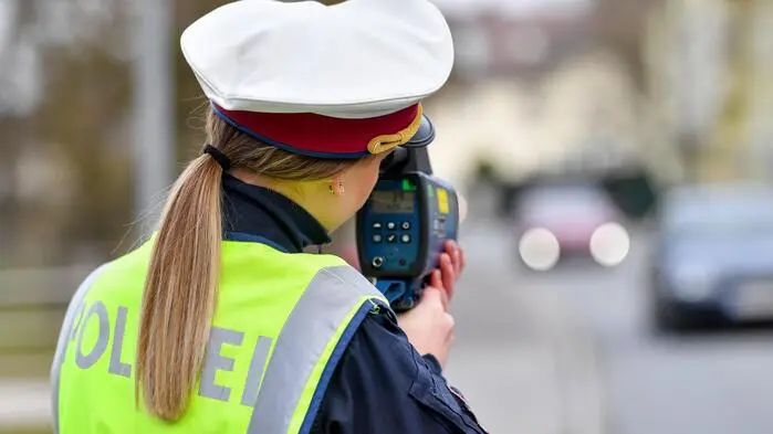 Man sieht eine Polizistin mit Lasermessgerät