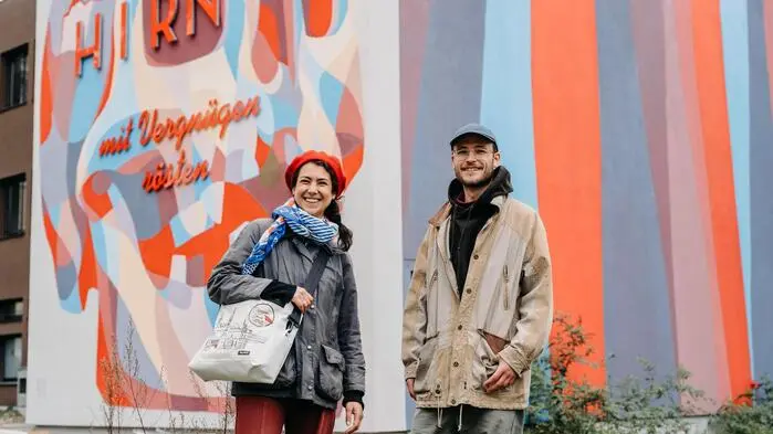 Ruth Nezmahen und Florian Perl  vor einer mit Graffiti verzierten Hausfassade