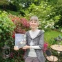 Auf dem Foto sieht man eine schlanke Frau in ihrem Garten, in der Hand hält sie ihr neuestes Kochbuch | Karin Sidak, begeisterte Köchin, Foodbloggerin und Kochbuch-Autorin