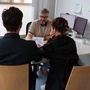 Zwei Personen sitzen bei der Caritas einem Sozialberater gegenüber