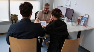 Zwei Personen sitzen bei der Caritas einem Sozialberater gegenüber