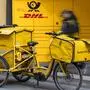 Ein DHL-Mitarbeiter mit einem gelben Lastenfahrrad | DHL war bereits der Markenname, ab 1. September heißt der ganze Konzern so